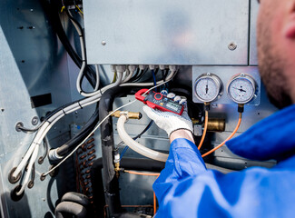 The technician checking power lines of the heat exchanger with current clamps