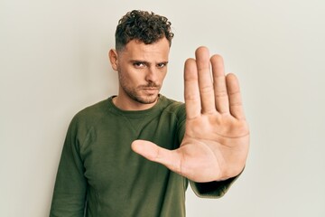 Young hispanic man wearing casual clothes doing stop sing with palm of the hand. warning expression...