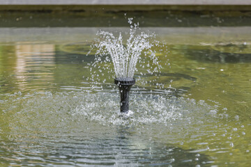 Small fountain in a city public park in the summer sunny day