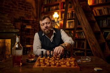 Man smokes a cigar and play chess in office