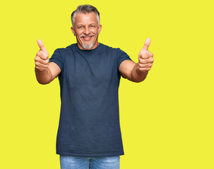 Middle age grey-haired man wearing casual clothes approving doing positive gesture with hand, thumbs up smiling and happy for success. winner gesture.