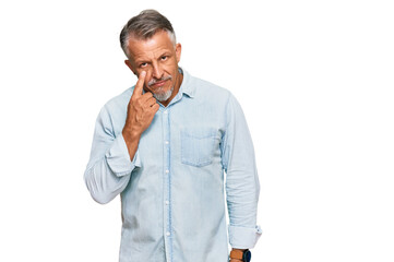 Middle age grey-haired man wearing casual clothes pointing to the eye watching you gesture, suspicious expression