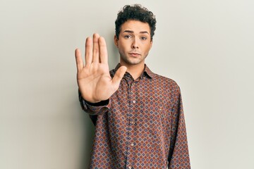 Handsome hispanic man wearing casual clothes doing stop sing with palm of the hand. warning...