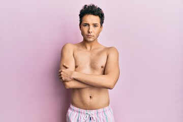 Young handsome man wearing swimwear shirtless skeptic and nervous, disapproving expression on face...