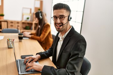 Obraz premium Two hispanic call center agents working at the office.