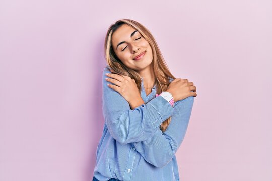 Beautiful hispanic woman wearing casual shirt hugging oneself happy and positive, smiling confident. self love and self care