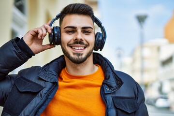 Handsome hispanic man with beard smiling happy and confident at the city wearing winter coat