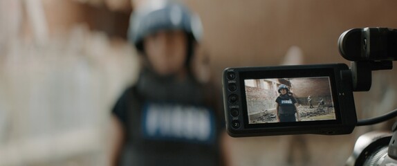 Behind the scenes of female war journalist correspondent wearing bulletproof vest and helmet...