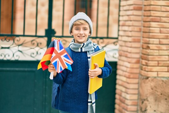 Adorable blond student kid smiling happy holding flags of different countries at the school.