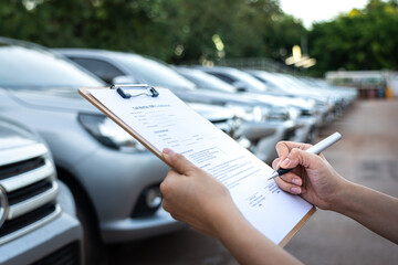 Action of a customer is signing on the agreement term of car rental service. Close-up and selective...