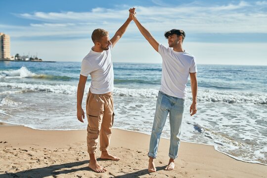 Young gay couple smiling happy dancing at the beach.