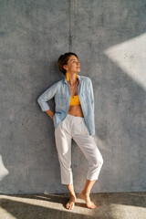 Obraz premium smiling happy beautiful woman posing against concrete wall on sunny day summer fashion style trend