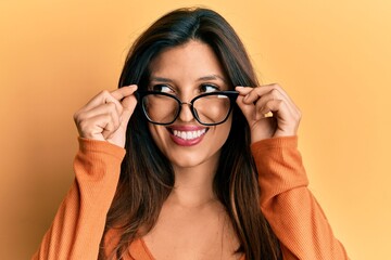 Beautiful hispanic woman wearing glasses smiling looking to the side and staring away thinking.