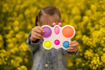 A child holds a popular toy popit rapeseed field. Useful toys for the development of fine motor skills of the fingers. Anti-stress toy. entertaining games for children. simple dimple. 