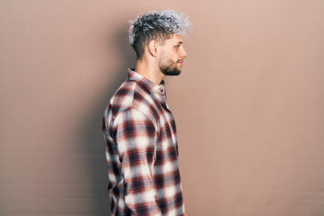 Young hispanic man with modern dyed hair wearing casual shirt looking to side, relax profile pose with natural face with confident smile.