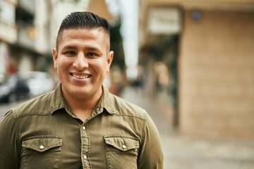 Young latin man smiling happy standing at the city.