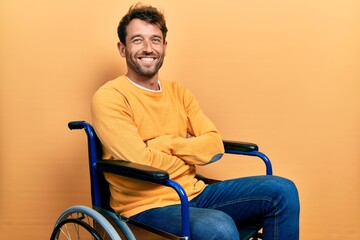 Fototapeta premium Handsome man with beard sitting on wheelchair happy face smiling with crossed arms looking at the camera. positive person.