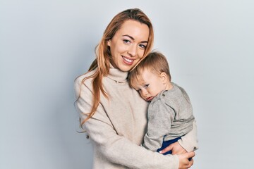 Young caucasian woman holding and hugging her son with love. Family of two bonding together. Mother holding infant toddler