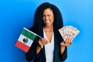 Middle age african american woman holding mexico flag and mexican pesos banknotes winking looking...