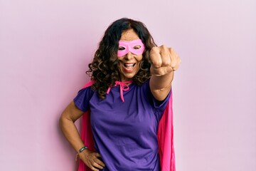 Middle age hispanic woman dressing as superhero wearing pink and purple feminist colors, smiling with confidence