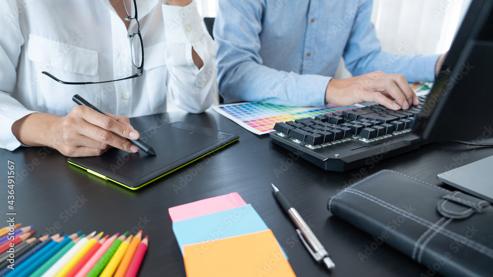 Poster graphic designer team working on web design using color swatches editing artwork using tablet and a 