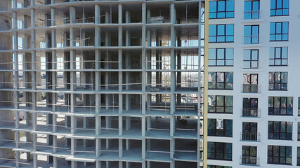 Aerial view of high residential apartment building under construction. Many windows on new apartment building facade under construction. Real estate development.