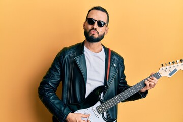 Young man with beard playing electric guitar looking at the camera blowing a kiss being lovely and sexy. love expression.