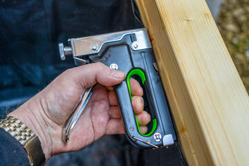 Close up of a carpenter using a brad nailer staple gun into wooden boards to repair  the inside...