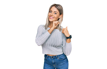 Beautiful blonde woman wearing casual clothes pointing to the back behind with hand and thumbs up, smiling confident