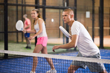 Padel player playing padel in a padel court indoor behind the net
