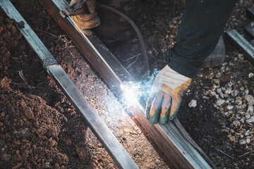 A welder welds metal at a construction site.