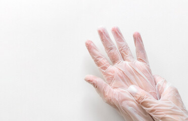 Two hands in transparent disposable vinyl gloves above white background with empty space from left...