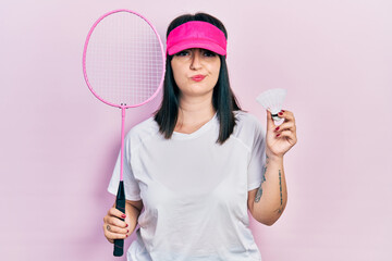 Young hispanic woman holding badminton racket and shuttlecock skeptic and nervous, frowning upset because of problem. negative person.