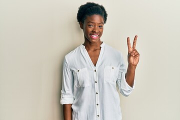 Young african american girl wearing casual clothes showing and pointing up with fingers number two while smiling confident and happy.