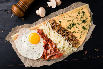buckwheat pancakes with mushroom sauce and fried eggs on a wooden background