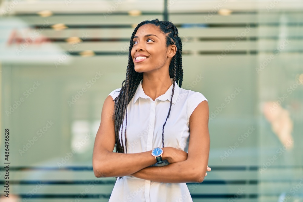 Poster Young african american woman with arms crossed smiling happy at the city.