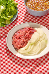 Summer party menu with beef, shrimp, roasted duck, fresh vegetable and sea grapes on red white caro background