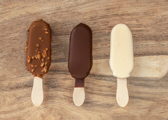 Stick ice cream on a wooden  background. Vanilla Eskimo Ice-cream bar. Popsicle and lolly sweet dessert. Top view . Summer concept. Copy space