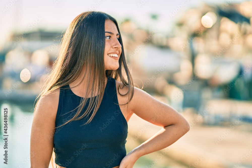 Wall mural Young hispanic girl smiling happy standing at the city.