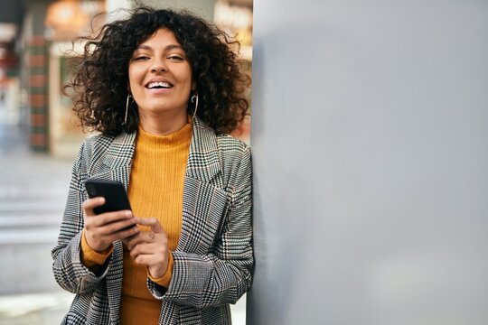 Young hispanic businesswoman smiling happy using smartphone at the city.