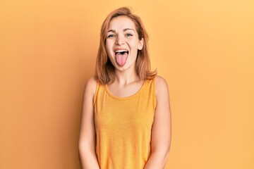 Young caucasian woman wearing casual style with sleeveless shirt sticking tongue out happy with...