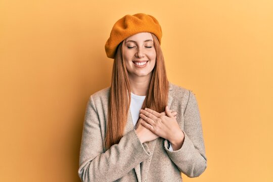 Young irish woman wearing french look with beret smiling with hands on chest with closed eyes and grateful gesture on face. health concept.