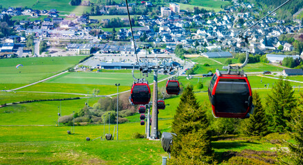 A cabin cable car travels up a mountain in summer