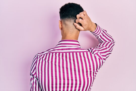 Young hispanic man wearing casual clothes backwards thinking about doubt with hand on head