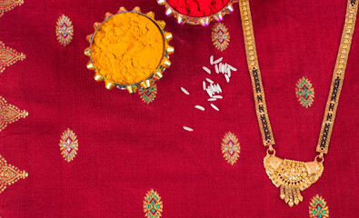 Mangalsutra or Golden Necklace to wear by a married hindu women, arranged with traditional saree with haldi, kumkum and flowers on plate