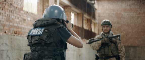 A soldier is posing for female war journalist inside destroyed building