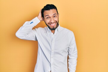 Hispanic man with beard wearing business shirt confuse and wonder about question. uncertain with doubt, thinking with hand on head. pensive concept.