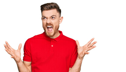 Fototapeta premium Young redhead man wearing casual clothes crazy and mad shouting and yelling with aggressive expression and arms raised. frustration concept.