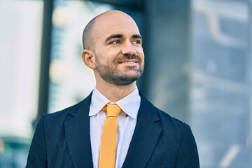 Fototapeta premium Young hispanic bald businessman smiling happy standing at the city.