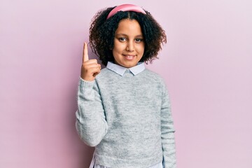 Young little girl with afro hair wearing casual clothes pointing finger up with successful idea. exited and happy. number one.